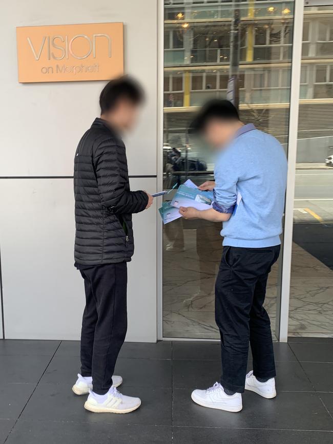 Two people with a wad of opened ballot papers outside the Vision on Morphett apartment building. Picture: Supplied