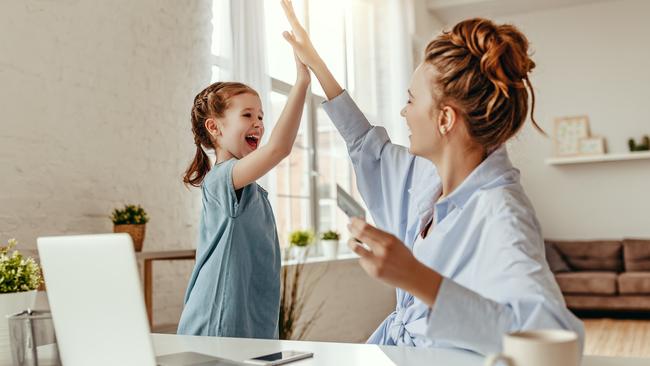 Low angle of excited small daughter giving high five to mother and screaming while celebrating successful online shopping using laptop at table in light living room Picture: Istock