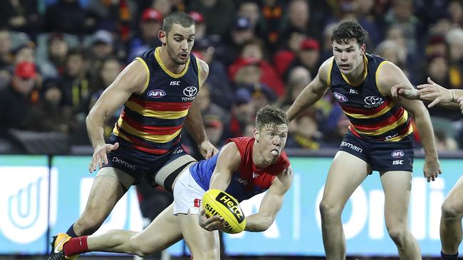 Melbourne’s Jake Melksham gets his handpass out as Crows players Taylor Walker and Mitch McGovern close in. Picture: SARAH REED