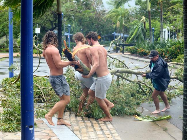 Airlie Beach locals Jayden Thacknay, 20, Raih Woodley, 22, and Rasa Lackey, 20, remove fallen branches from the main street as the eye of cyclone Debbie passes over. Picture: Liam Kidston