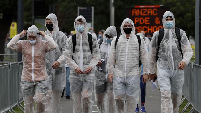 Fans arrive well covered in masks and rain gear. Picture: Nikki Short