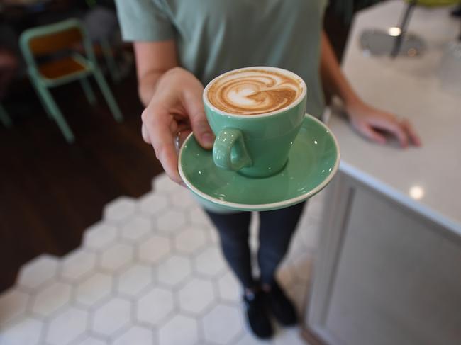 A waitress is seen holding a coffee at a cafe in Canberra, Thursday, Feb. 23, 2017. The Fair Work Commission today announced cuts to Sunday and public holiday penalty rated in the retail and hospitality industries. (AAP Image/Lukas Coch) NO ARCHIVING