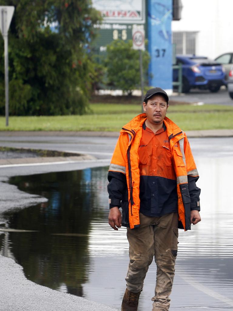 Paul Lim from Century Cranes walks past the floodwater on Aumuller St PICTURE: ANNA ROGERS