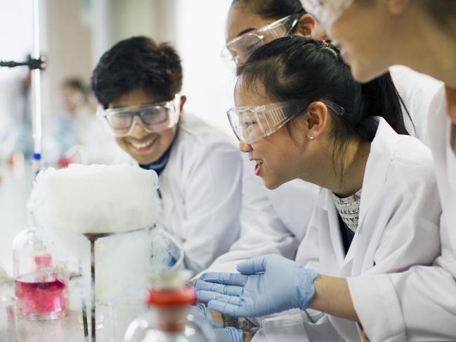 Curious students watching chemical reaction, conducting scientific experiment in laboratory classroom