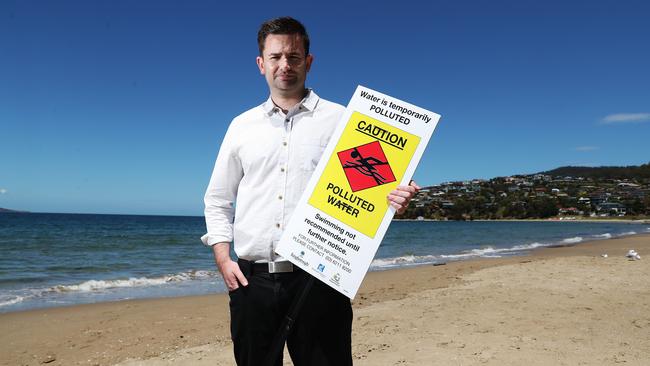 Kingborough Mayor Dean Winter with a polluted water sign at Blackmans Bay Beach. Picture: NIKKI DAVIS-JONES