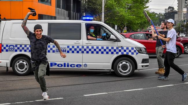 Men stand in front of a police van with a sign. Picture: Jake Nowakowski