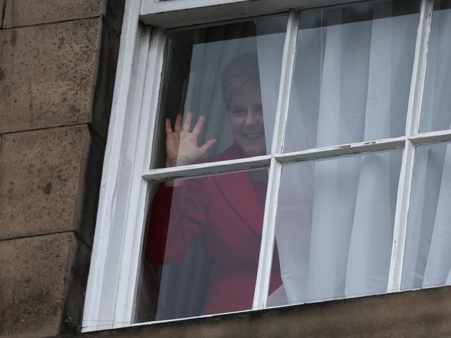 Nicola Sturgeon waves from a window, after holding a press conference to announce her resignation. Picture: Jeff J Mitchell/Getty Images.