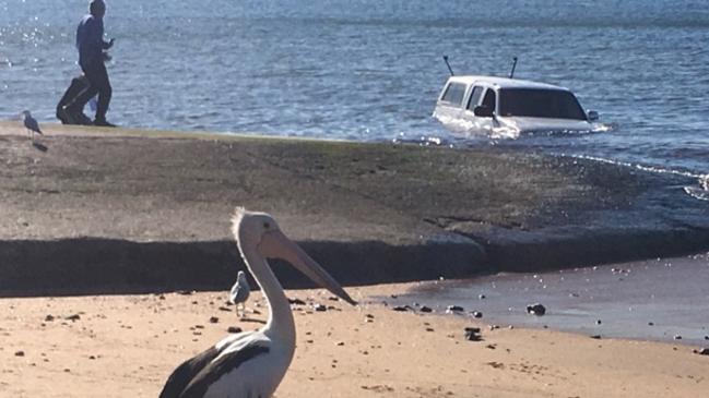 A ute wallows in the waves after rolling off the Long Reef boat ramp on Fishermans Beach at Collaroy.