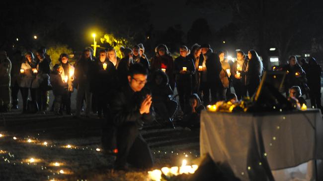 A man prays before a makshift shrine at a gathering to support the family of Qi Yu in Berowra. Picture: Jake McCallum