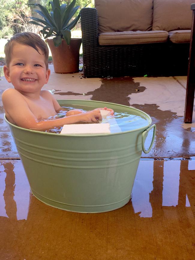 When you get a little older, the sink won’t fit ... three-year-old Sam Hudson cools off in the 41C heat in Roxby Downs. Picture: Amanda Hudson