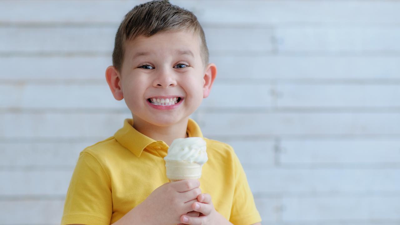 The boy bite into ice cream and smiling broadly at the camera