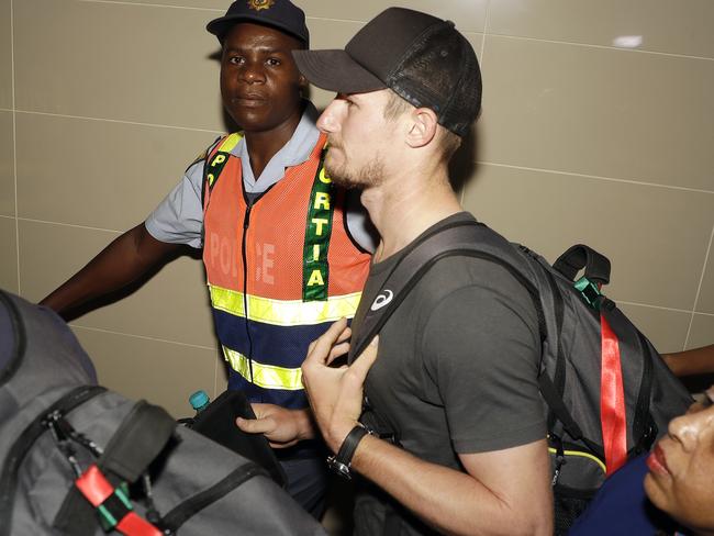 Cameron Bancroft, 25, is escorted by police officers to the departure area at OR Tambo International airport after his former captain. Picture: AP Photo/Themba Hadebe