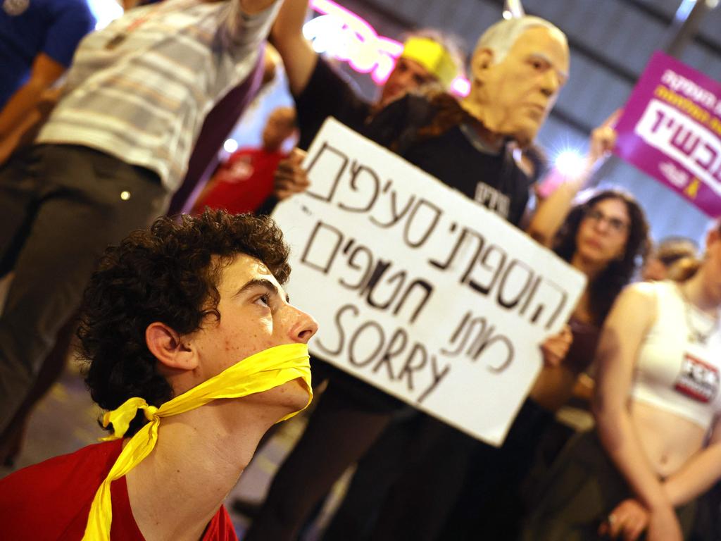 Demonstrators hold placards as a man sits with his mouth bound during an anti-government protest directed at Mr Netanyahu. Picture: AFP