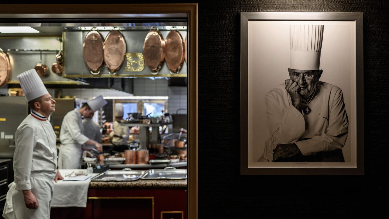 Chef Gilles Reinhardt works beside a portrait of Paul Bocuse at Auberge de Collonges in France, paying homage to Bocuse’s legacy. Picture: Jeff Pachoud/AFP