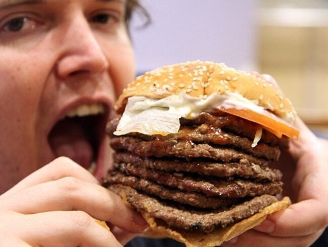 A tourist tries the Burger King 'Windows 7 Whopper' hamburger with seven meat patties in Tokyo. Picture: Splash.