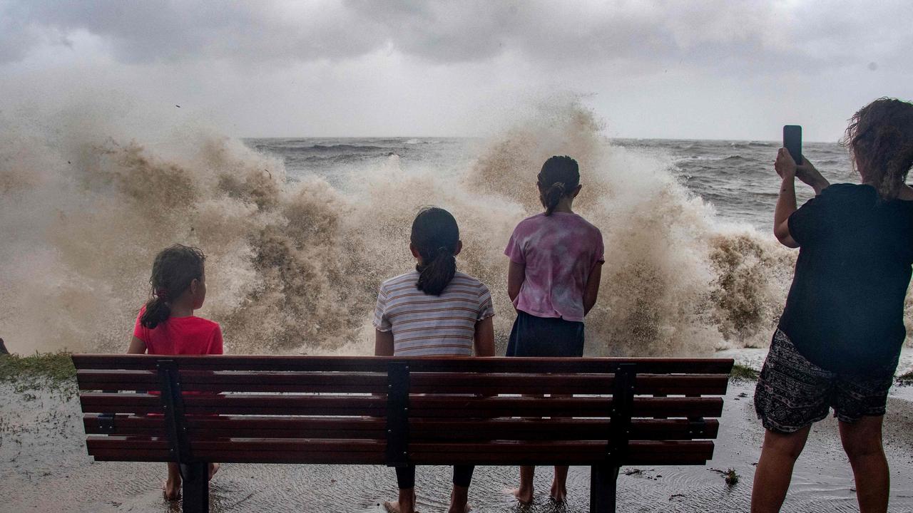 A family watch the storm roll in across the Coral Sea at Holloways Beach as Cyclone Jasper approaches landfall in Cairns. Picutre: Brain Cassey