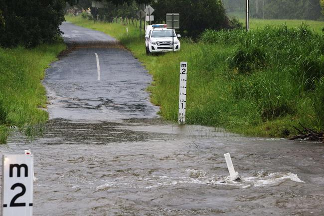 An abandoned police car sits on the other side of the water on Tallebudgera Creek Rd after police were left stranded by rising floodwaters and had to wait until morning to walk out. Picture: Glenn Hampson.