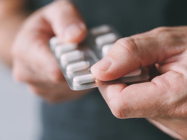 Man taking medicine from blister pack, closeup of hands with selective focus