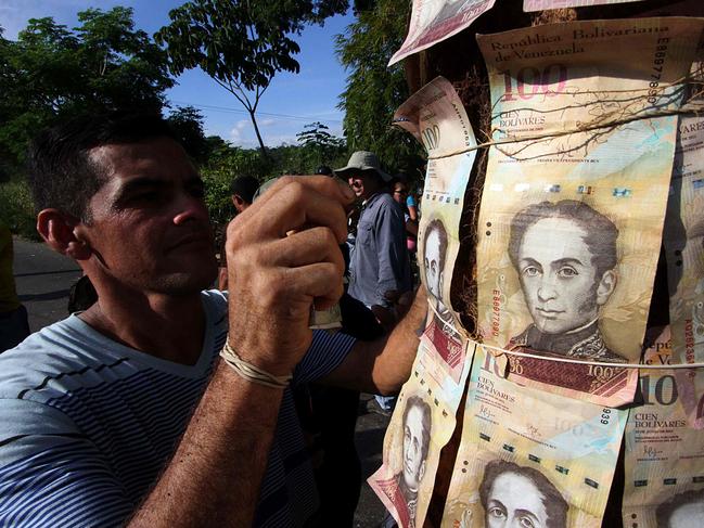 People show 100-Bolivar notes during a protest over lack of cash as the new bank notes have not yet appeared, at the "Troncal 5" road in San Cristobal in Venezuela's Tachira state, on December 16, 2016. Venezuelans lined up to deposit 100-unit banknotes before they turned worthless, but replacement bills had yet to arrive, increasing the cash chaos in the country with the world's highest inflation. Venezuelans are stuck in currency limbo after President Nicolas Maduro ordered the 100-bolivar note -- the largest denomination, currently worth about three US cents -- removed from circulation in 72 hours. / AFP PHOTO / GEORGE CASTELLANOS