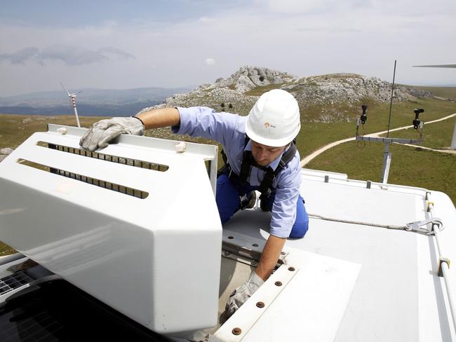 An employee wears a safety harness and hard hat as he checks the oil cooling system on the top of a wind turbine unit manufactured by Gamesa Corp. Tecnologica SA and operated by Enel Green Power SpA, the clean-energy unit of Italy's biggest utility Enel SpA at their wind farm in Frosolone, Italy, on Tuesday, July 29, 2014. Enel SpA, Italy's largest utility, will steer investments into Latin America and renewable energy as recession damps electricity demand in its biggest market. Photographer: Alessia Pierdomenico/Bloomberg