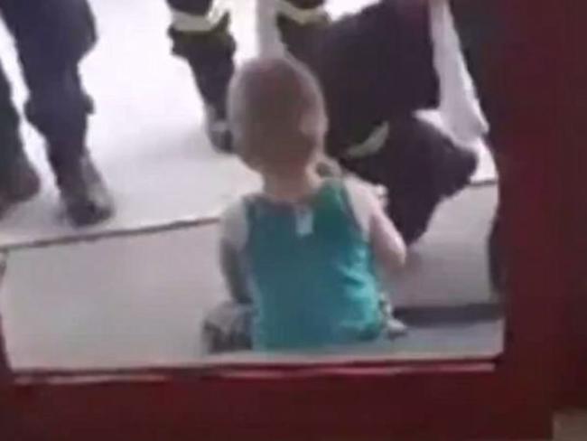 The boy sits with emergency services after being rescued.