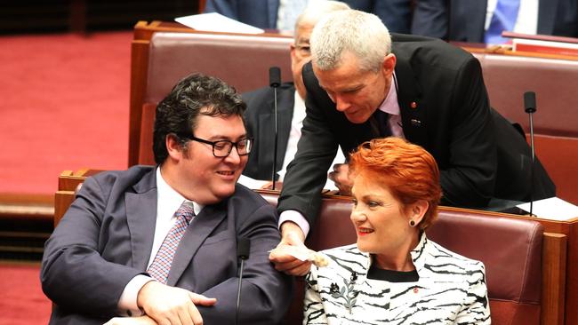 Senator Pauline Hanson and George Christensen are offered a bag of cashews from Malcolm Roberts in Parliamanet. Picture: Gary Ramage