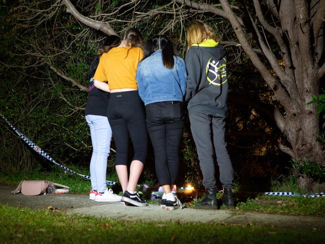 A group of girls pay their respects and lay flowers at the scene of a tragic shooting in West Pennant Hills.