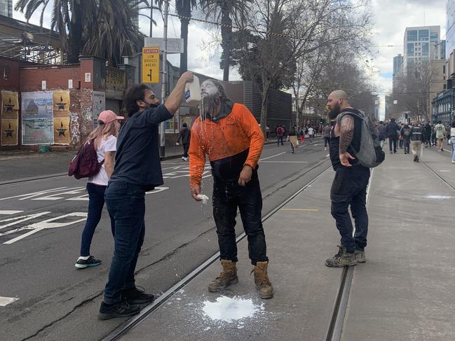 A man has milk poured on his face after being doused with pepper spray.