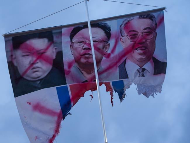 A banner showing the defaced photos of North Korean leaders Kim Jong-un, Kim Jong-il, and Kim Il-sung is displayed during a rally against a performance by North Korean musicians in Seoul. Picture: Jenni Lim/AFP