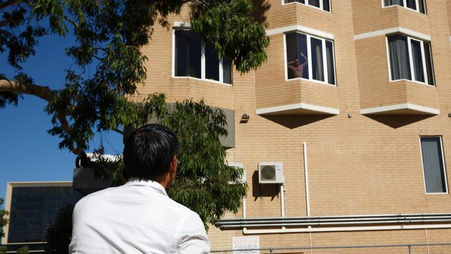 A man in quarantine at the Four Points hotel in Perth speaks with a friend standing on the street. Picture: AFP