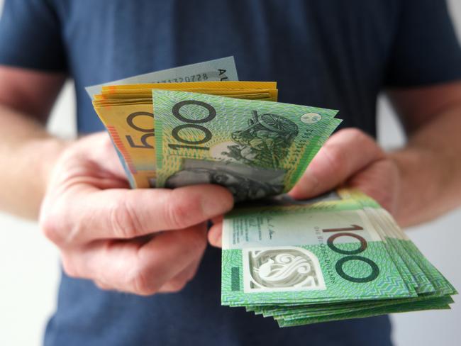 A man counting Australian dollar bills. A picture that describes buying, paying, handing out money, or showing money. Australian cash money generic