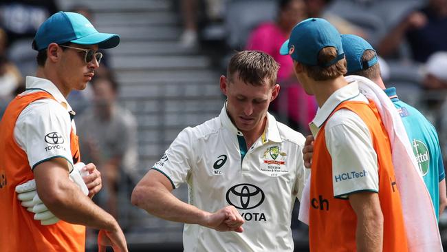 Australia's Marnus Labuschagne (C) inspects his injured finger during day three. Picture: AFP