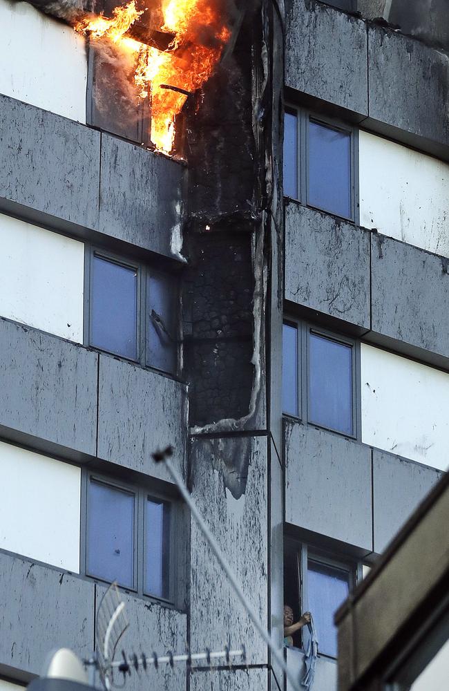 A person, bottom right, peers out of a window from the fire. Picture: AP