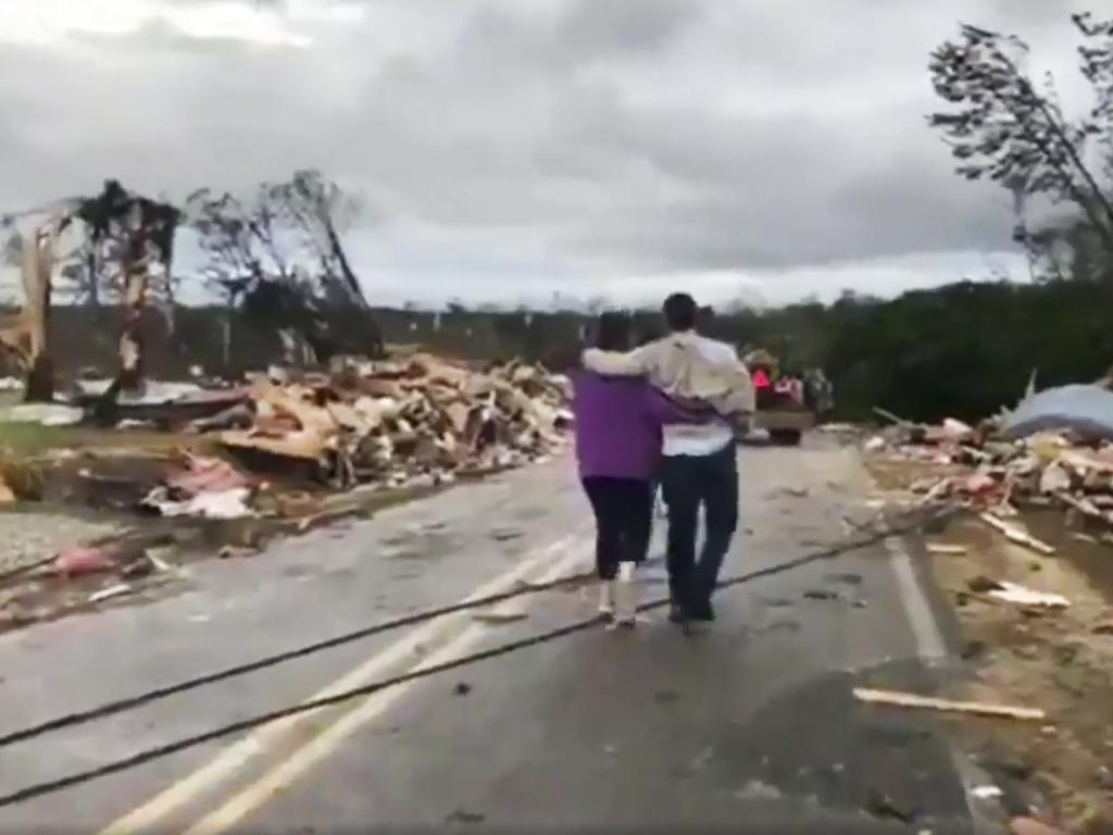 People walk amid debris in Lee County after what appeared to be a tornado struck in the area. Picture: AP