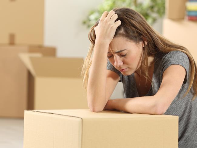 Sad homeowner moving home after eviction sitting on the floor of the living room at home