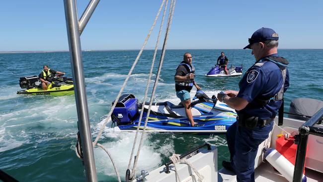 David Burgess checks a boat and fishing licenses of jetski riders during a 2019 patrol. Picture: Mike Dugdale