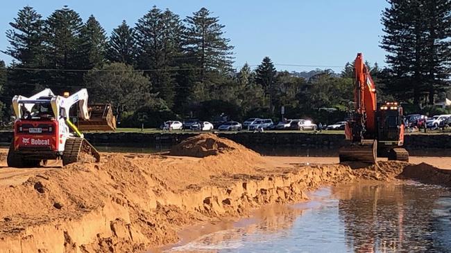 Excavators work to create a channel from Narrabeen Lagoon to the ocean ahead of an expected east coast low to affect the northern beaches this weekend. Picture: Jim O'Rourke