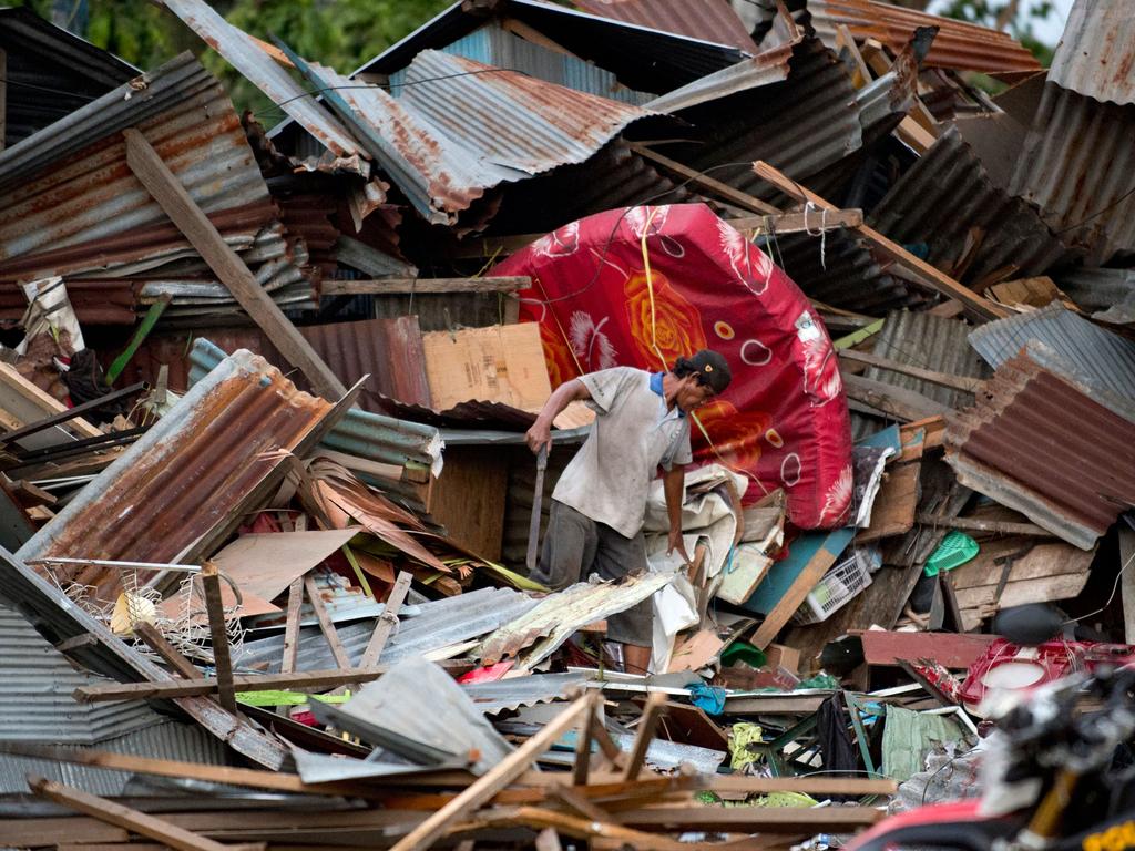 A man looks for his belongings amid the debris of his destroyed house. Picture: AFP