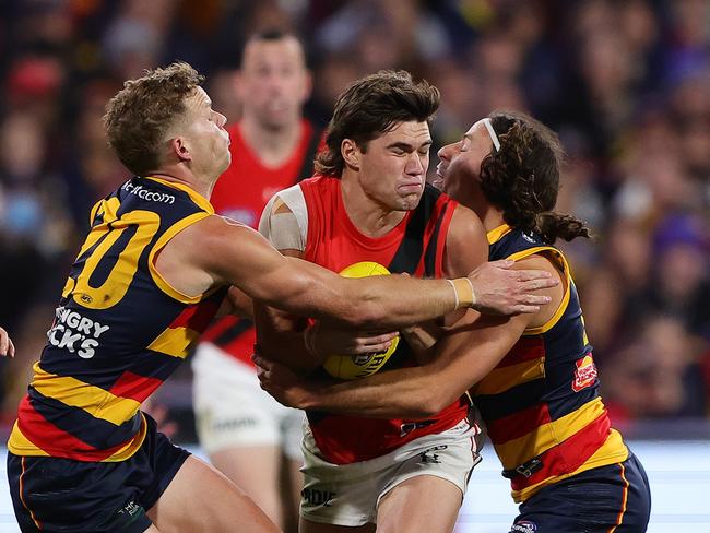 ADELAIDE, AUSTRALIA - APRIL 19: Sam Durham of the Bombers sandwiched between Mitchell Hinge of the Crows and Will Hamill of the Crows during the 2024 AFL Round 06 match between the Adelaide Crows and the Essendon Bombers at Adelaide Oval on April 19, 2024 in Adelaide, Australia. (Photo by Sarah Reed/AFL Photos via Getty Images)