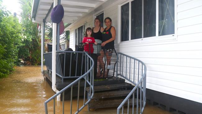 Trisha and Hayley Murphy with Penni Lea Baxter on the porch of their Mossman St home totally surrounded by rising waters of the Mossman River. Picture: Peter Carruthers