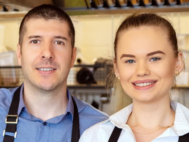 CAREERS FOR MAY 2: Portrait of small business owner smiling behind counter inside eatery, Successful young waiters working in apron holding food order for home delivery