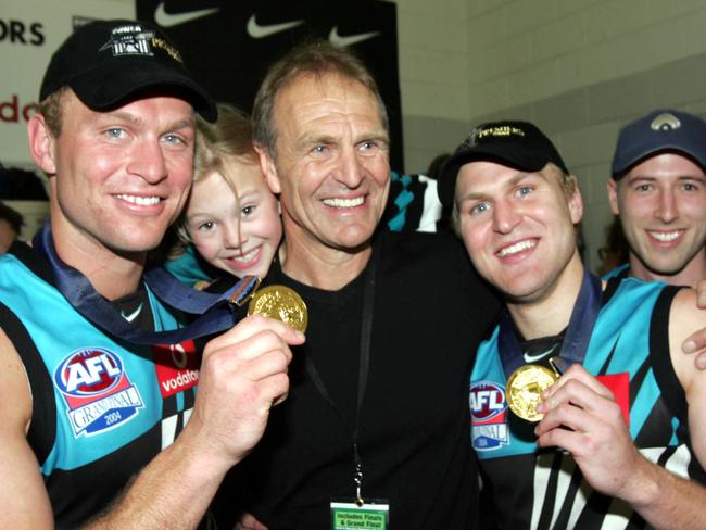 Kane (right) celebrates Port’s 2004 premiership win with dad Graham and fellow player and brother Chad.