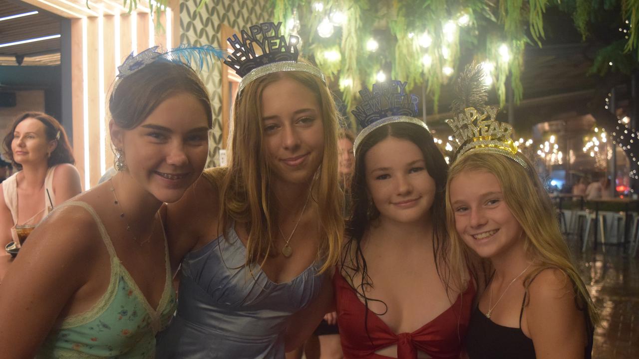 Charlie Harris (13), Bella Eldon (15), with Laura and Mackenzie O'Keefe sheltered from the rain during New Year celebrations in Airlie Beach. Picture: Laura Thomas