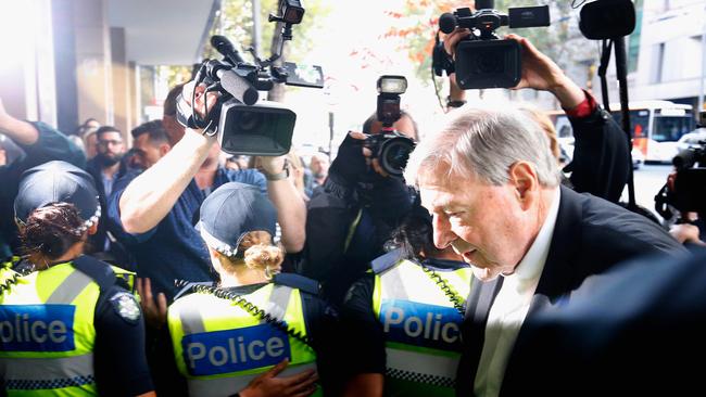 Cardinal George Pell walks through a police guard at Melbourne Magistrates’ Court. Picture: Darrian Traynor/Getty Images                        <a class="capi-image" capiId="eb43cb37ddbee2426e33861cf56d8f3f"></a>