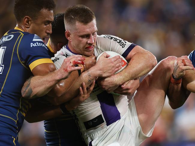 SYDNEY, AUSTRALIA - MARCH 02: Cameron Munster of the Storm Is tackled by Jirah Momoisea and Josh Hodgson of the Eels during the round one NRL match between the Parramatta Eels and the Melbourne Storm at CommBank Stadium on March 02, 2023 in Sydney, Australia. (Photo by Cameron Spencer/Getty Images)