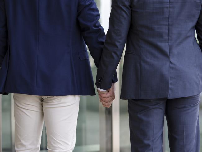 two men in suits standing and holding hands