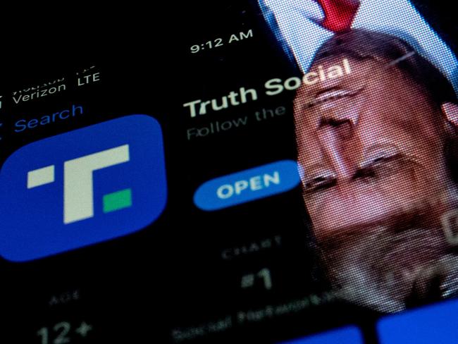 Donald Trump is reflected in a phone screen displaying the Truth Social app. Picture: Stefani Reynolds/AFP