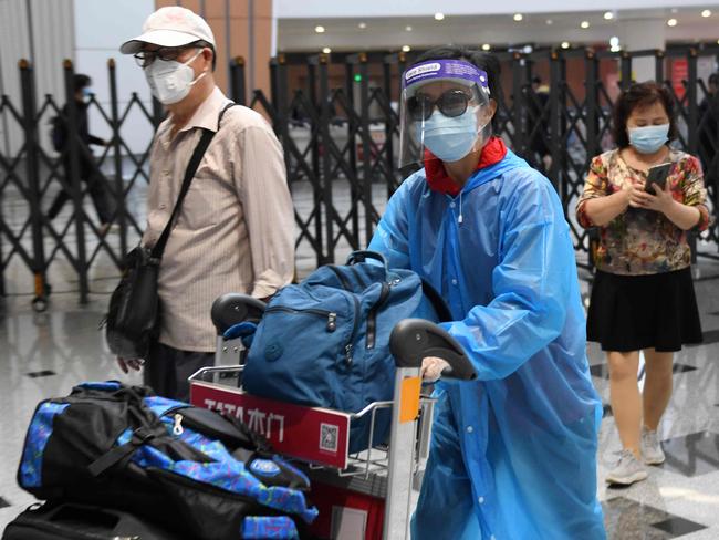 Travelers wear face masks amid concerns of the COVID-19 coronavirus as they arrive from a flight at Beijing Daxing Airport on the eve of a five-day national holiday on April 30, 2020. (Photo by GREG BAKER / AFP)