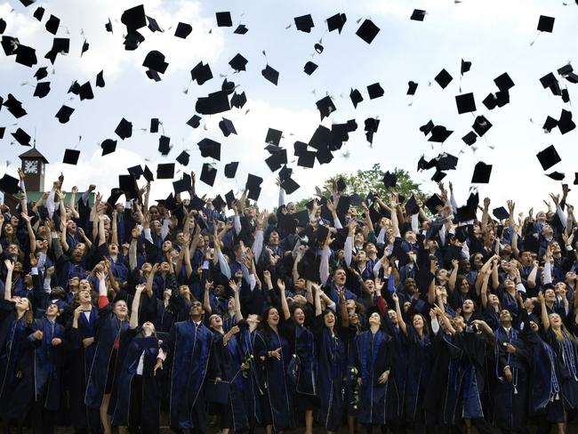 Graduating university students throw their mortarboard caps in the air at ceremony.