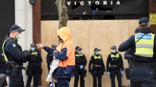 Police question tradies outside the CFMEU offices in Melbourne after yesterday's violent protests against mandatory vaccinations for workers on building sites. Picture: NCA NewsWire / Andrew Henshaw